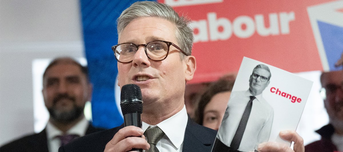 Keir Starmer holding copy in hand while speaking on mic